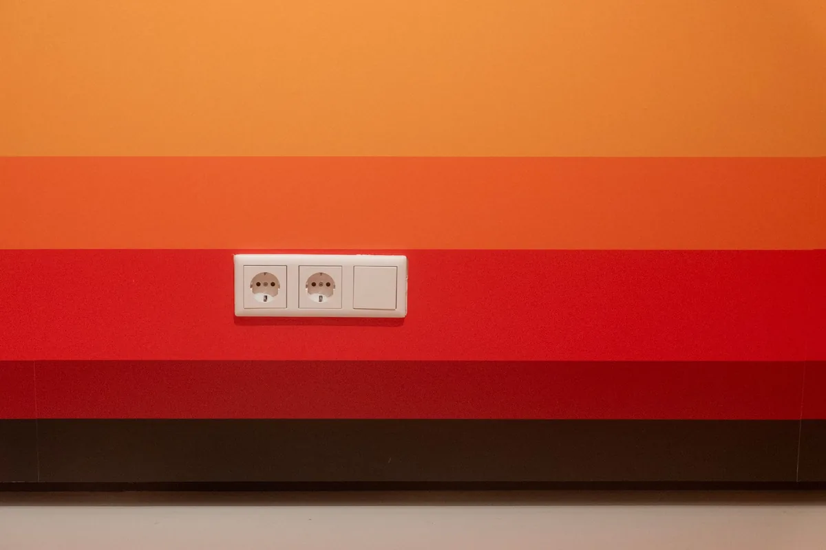 A double wall socket on a striped orange and red wall