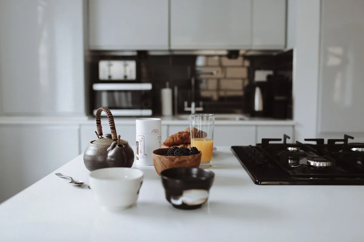 A white kitchen counter with a kettle and a gas hob