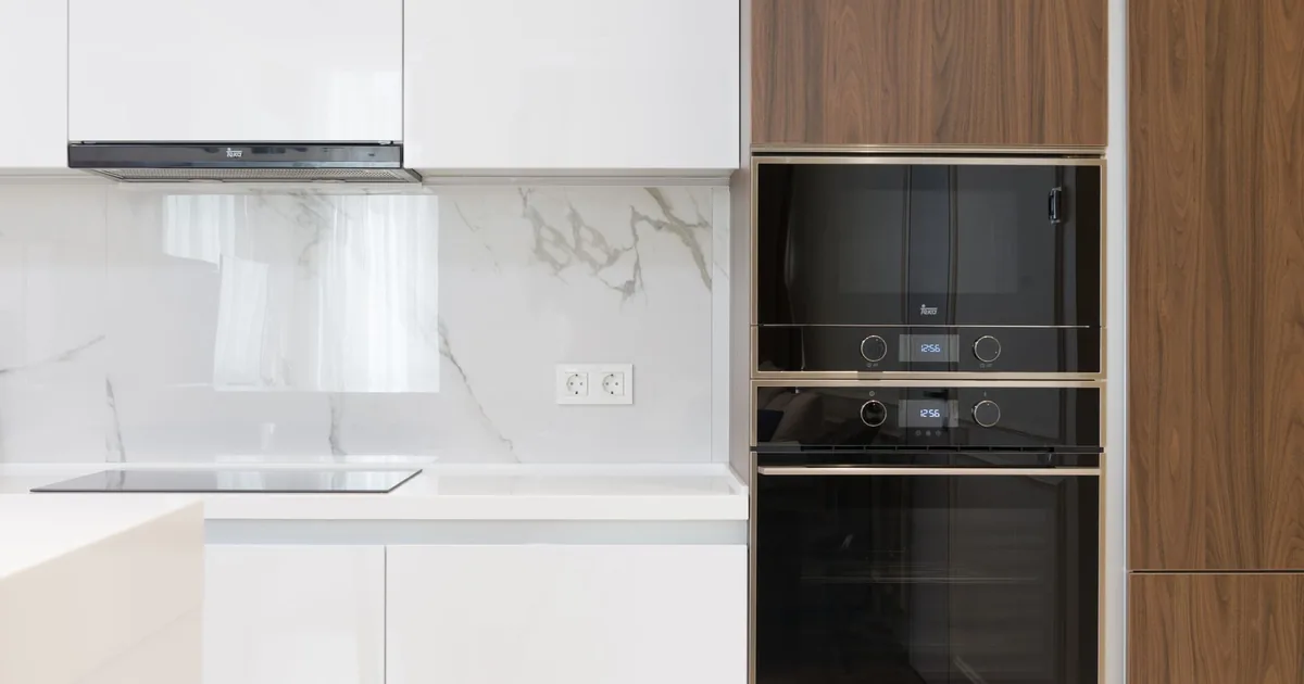 A white kitchen with a built-in oven and microwave