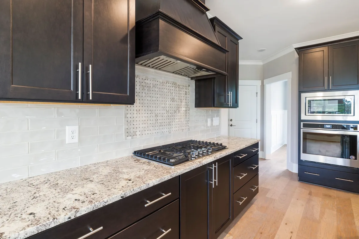 A kitchen with dark cabinets and a gas cooktop