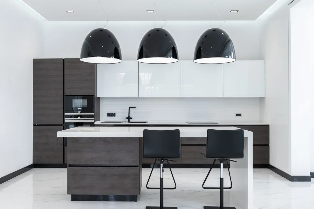 A white kitchen with pendant lights and an island with stools