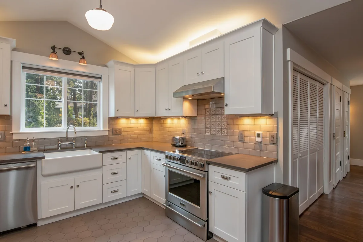 A white kitchen with under-cabinet lights and a range