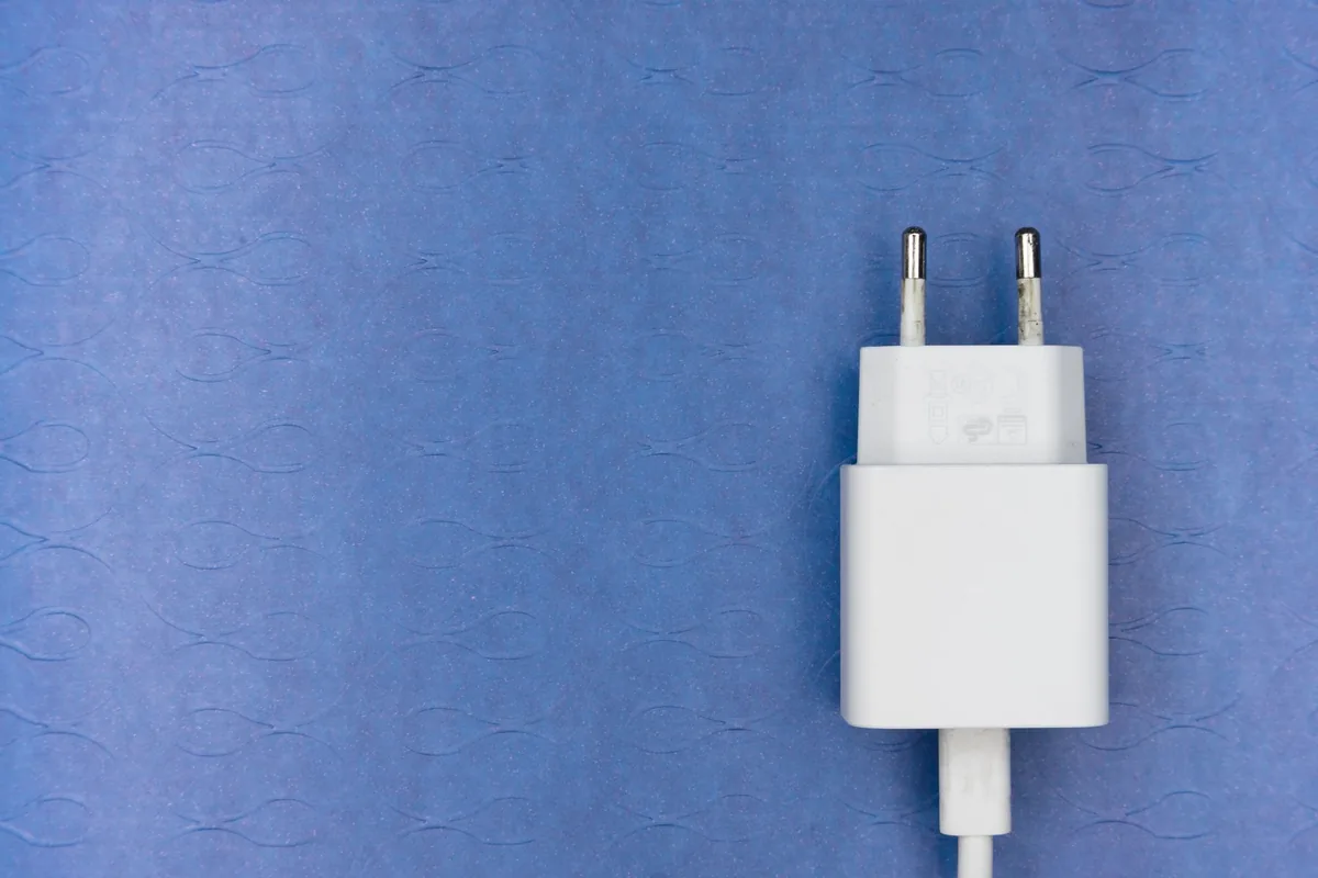 A white plug adapter with its cable on a blue background