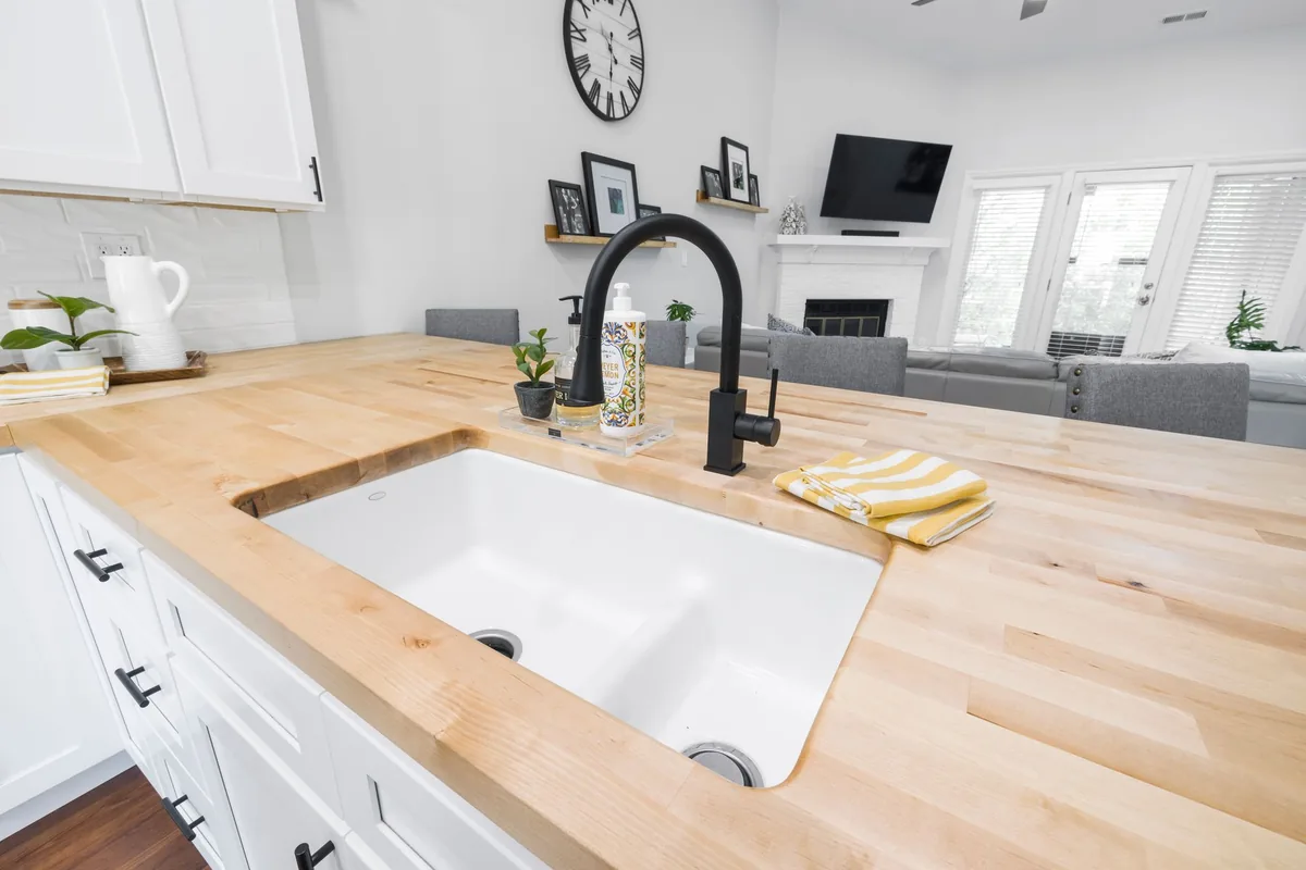 A white sink in a butcher-block counter with a black faucet
