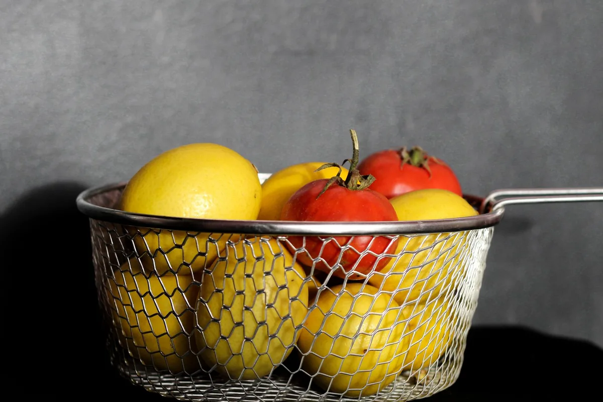 A wire basket of lemons and tomatoes