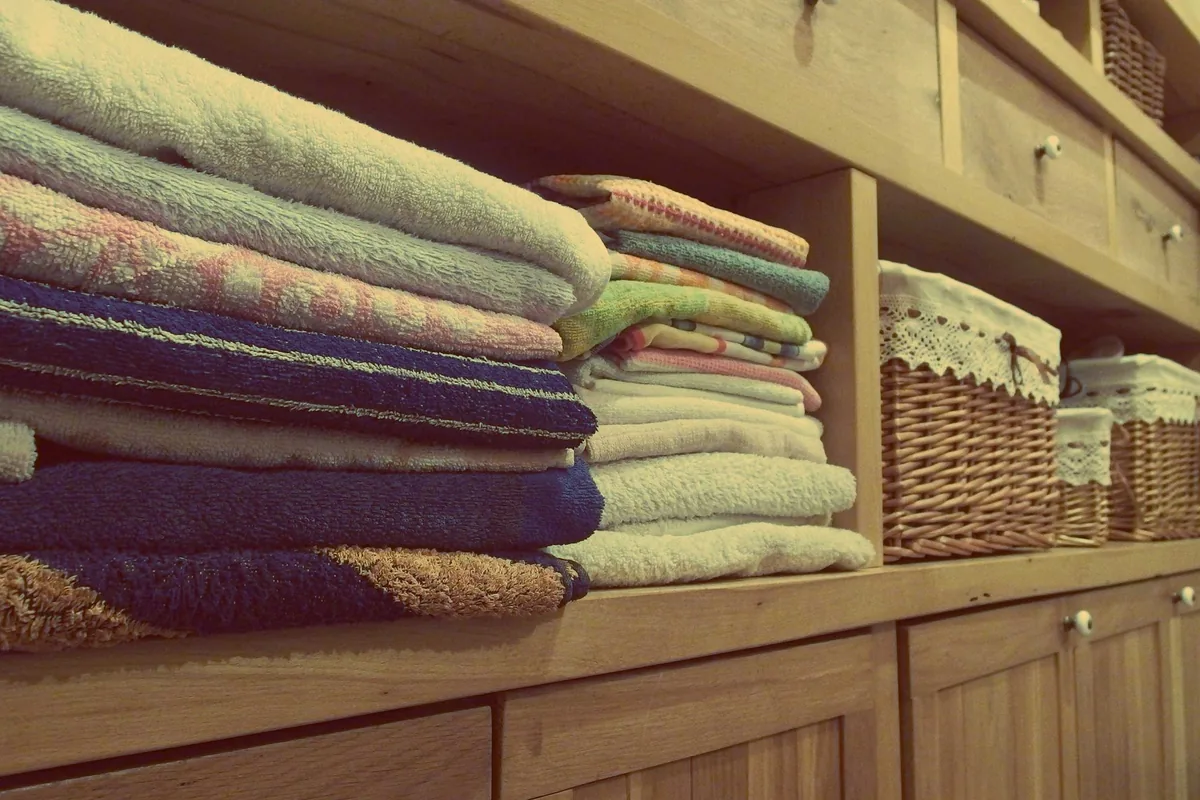 A woven laundry basket holding neatly folded light-coloured linens