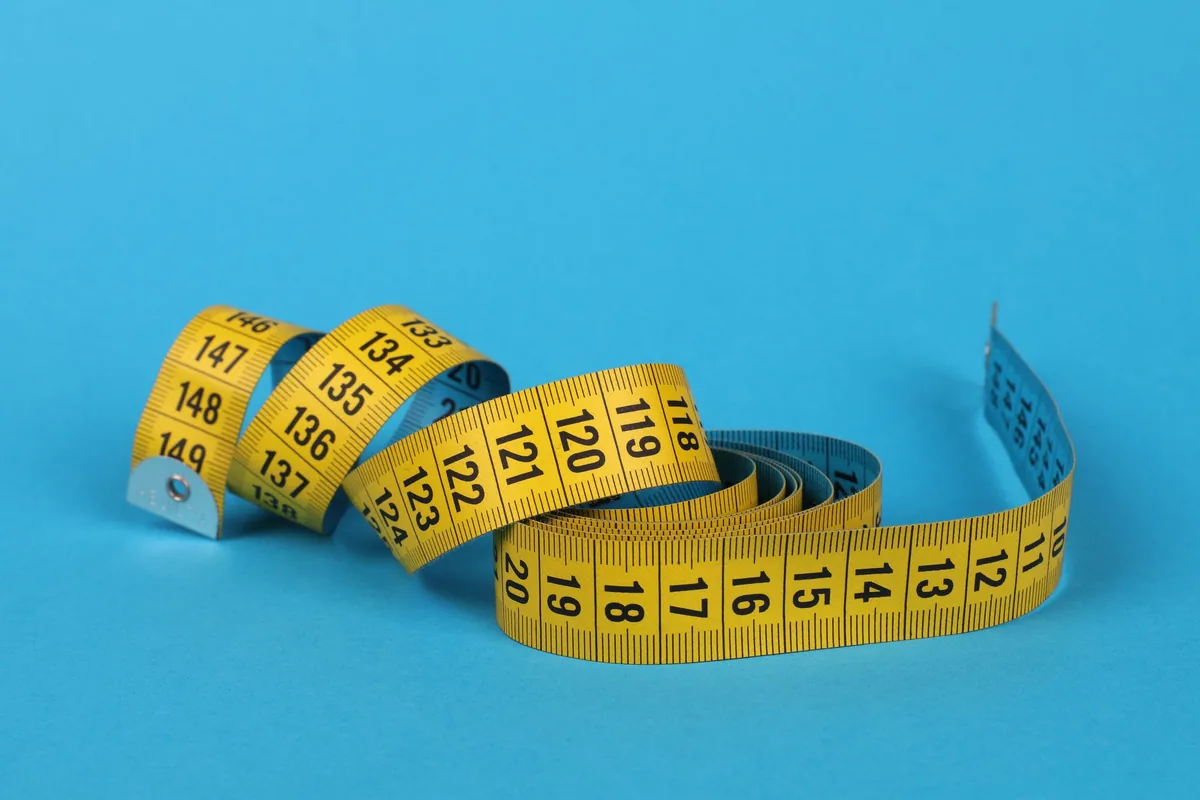 A yellow tape measure coiled on a blue surface