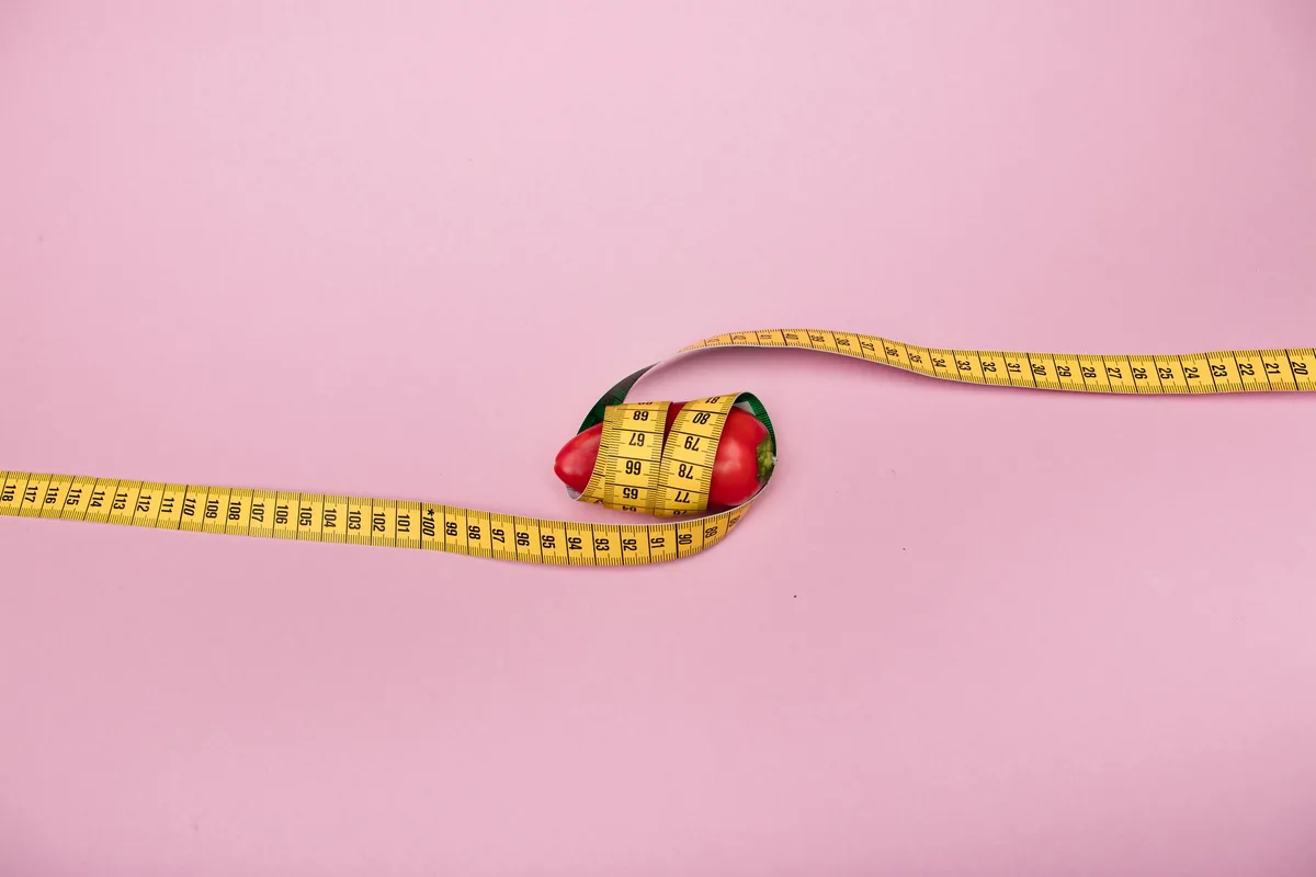 A yellow tape measure on a pink background