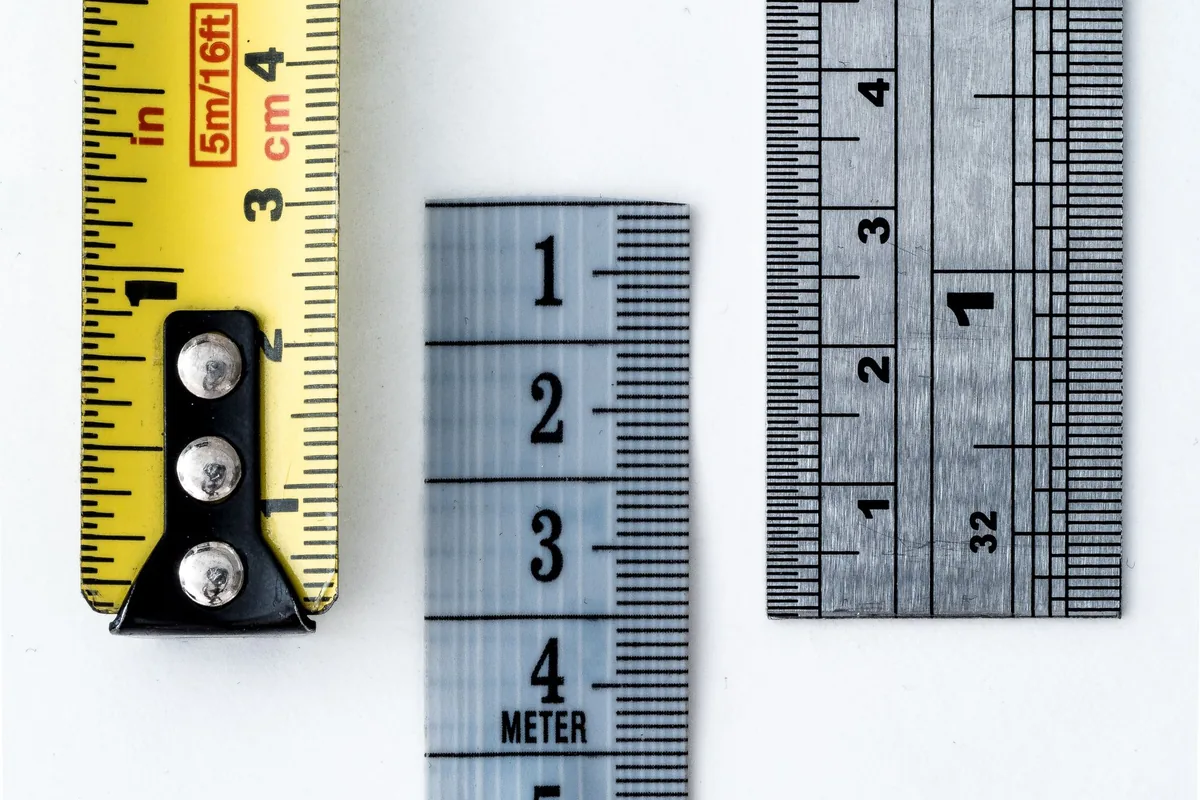 A tape measure beside two steel rulers