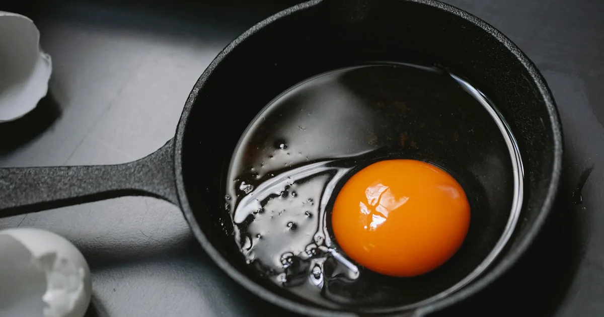 An egg frying in a cast iron pan