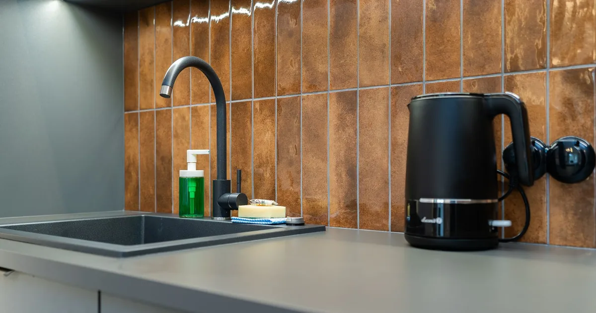 An electric kettle releasing steam on a kitchen counter