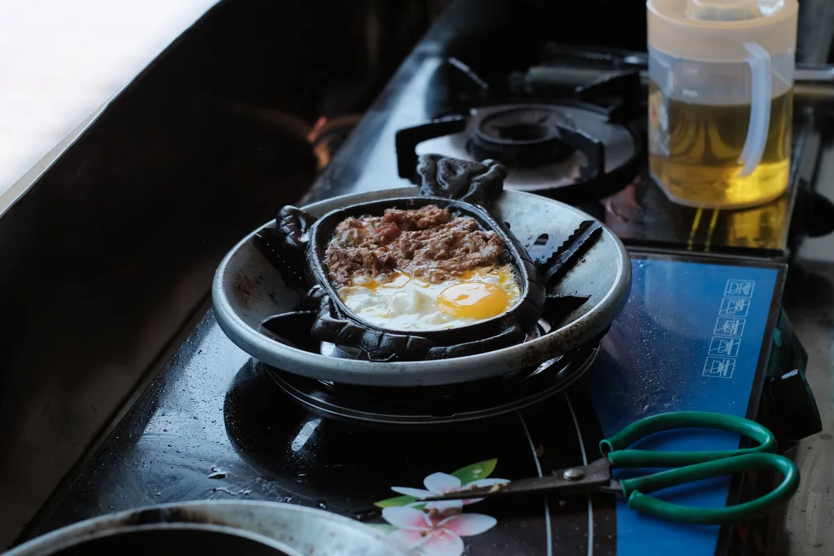 A small cast iron pan with an egg on a gas burner