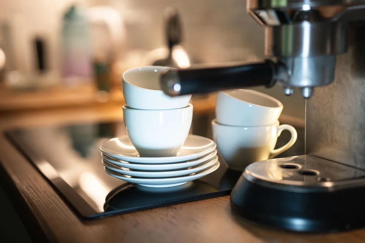 An espresso machine group head above a stack of cups