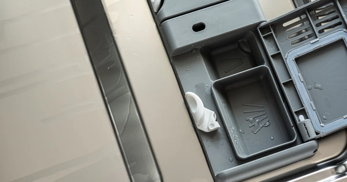 An open dishwasher door showing the detergent dispenser