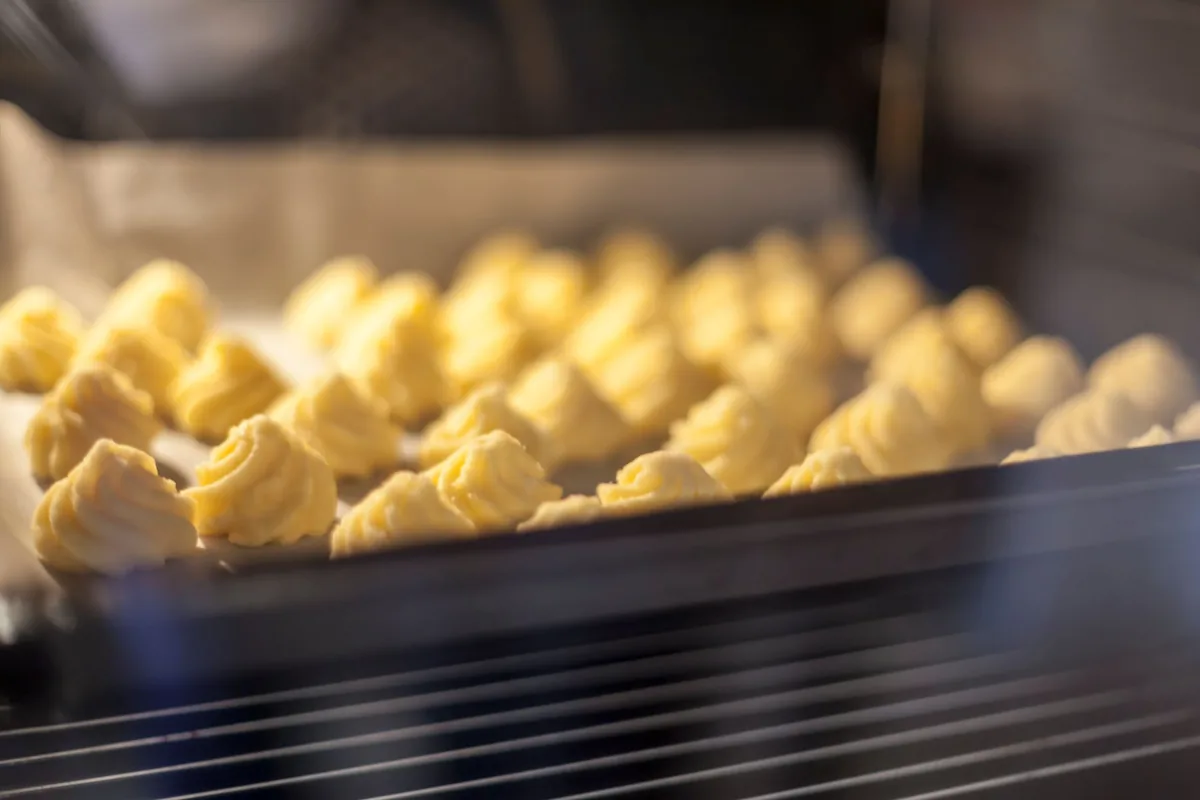 Choux pastry on a baking tray inside an oven