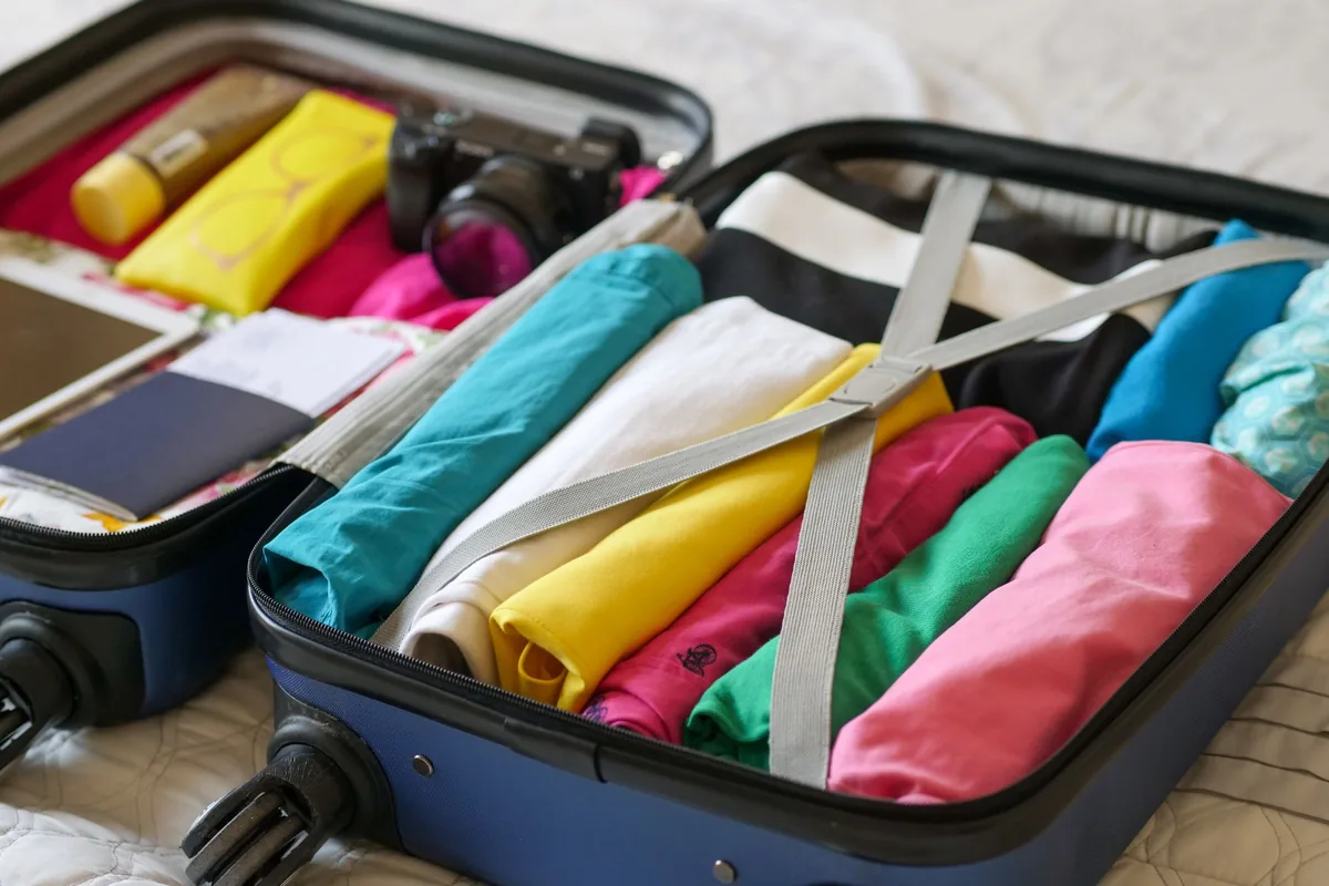 An open suitcase on a bed with neatly folded clothes and a toiletry bag