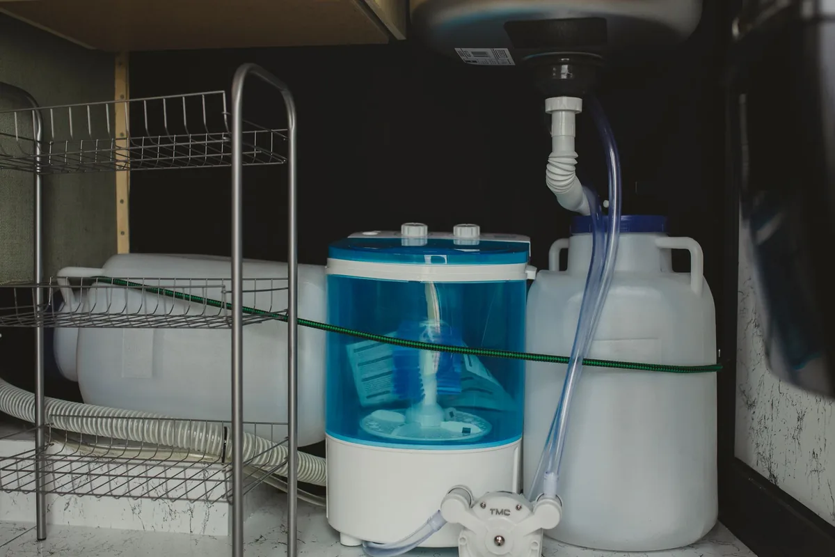 Water filter canisters and tubing inside a cabinet under a sink