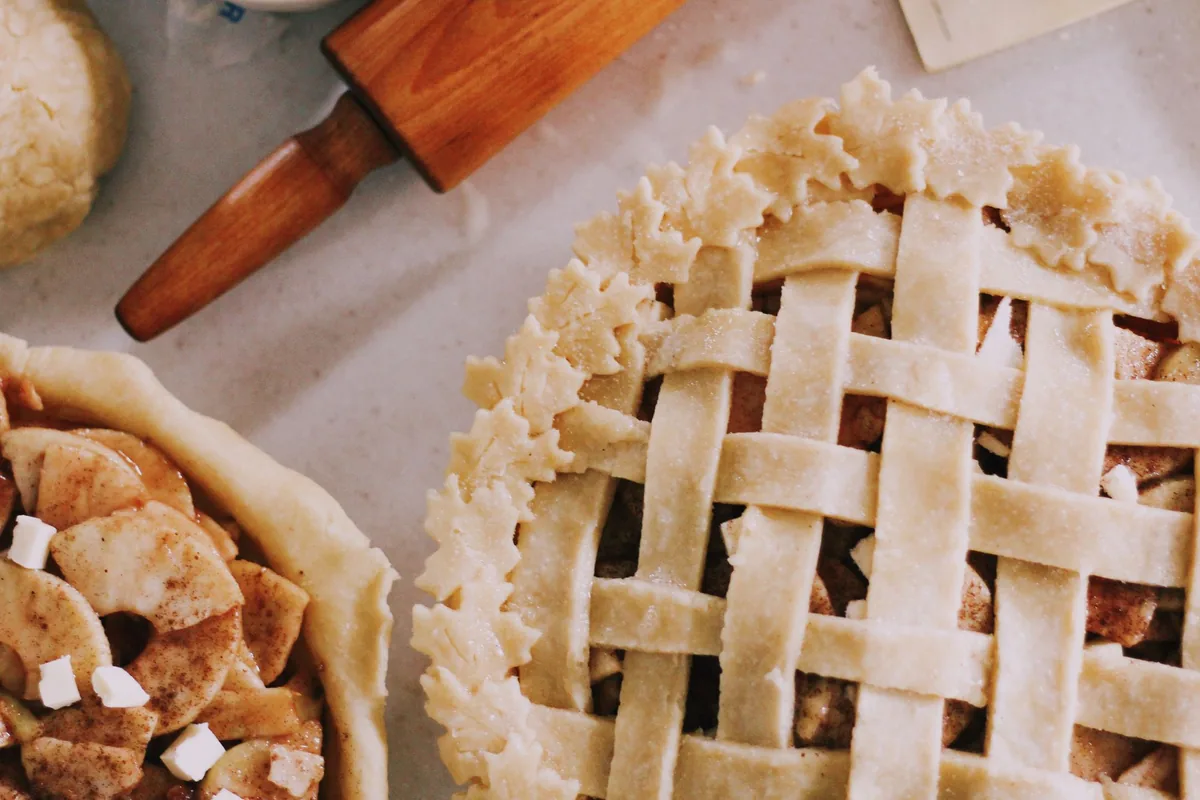 An unbaked pastry crust pressed into a clear glass pie plate on a floured counter