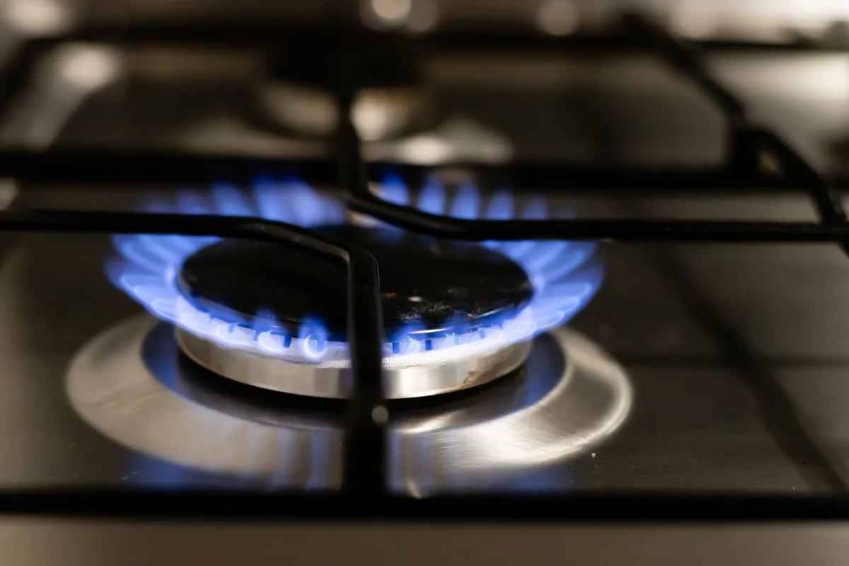 Blue flames burning on a gas burner beneath a black stovetop grate