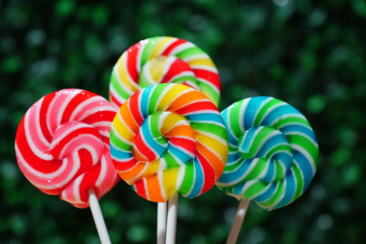 Bright hard candy lollipops laid out on a white surface