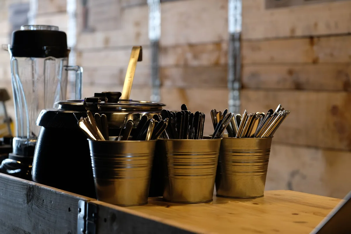 Brushed stainless steel cooking tools gathered in a metal holder beside a stove