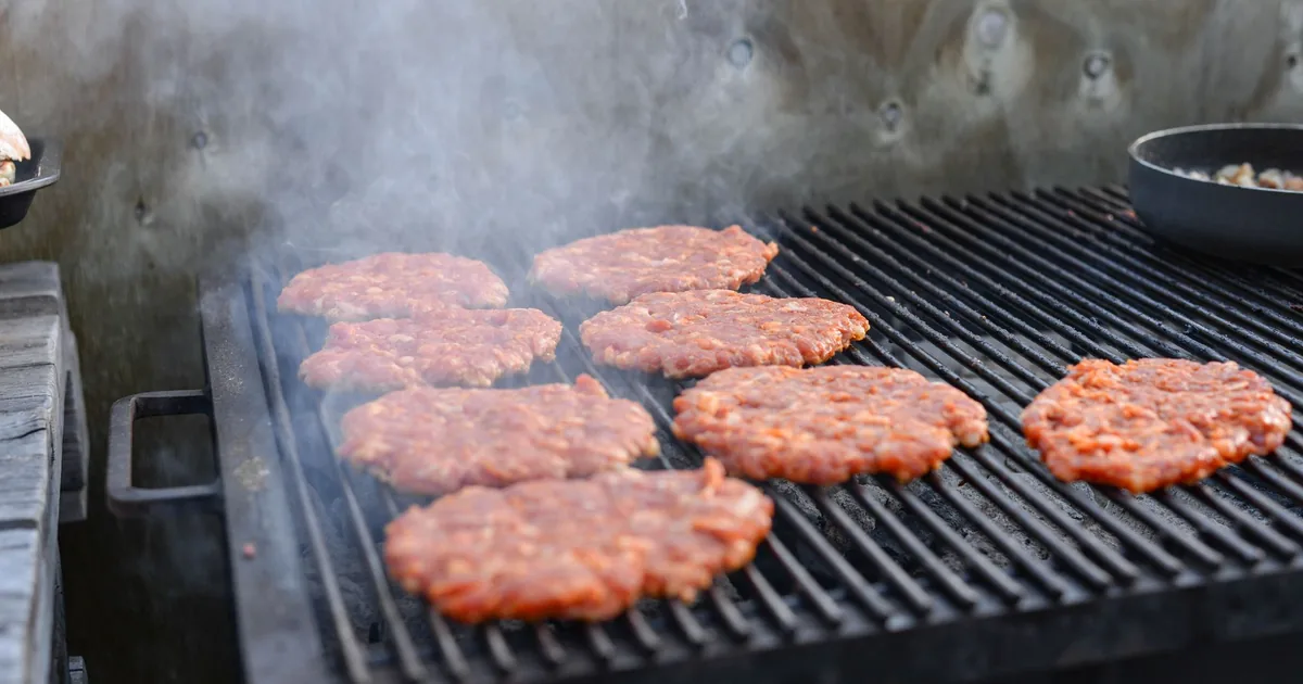 Burger patties lined up on a commercial grill