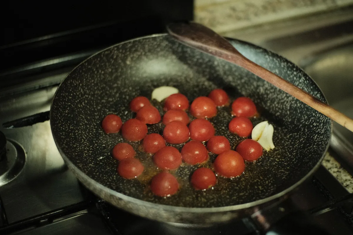 Cherry tomatoes cooking in a dark pan