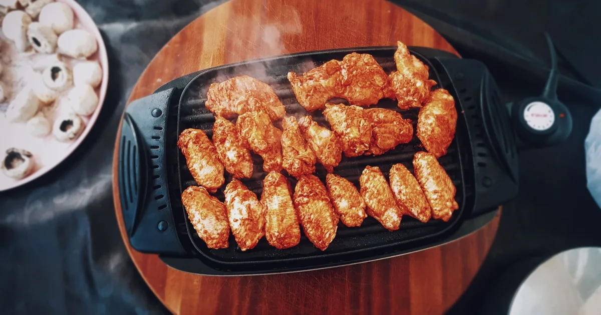 Chicken pieces on a round ridged grill pan