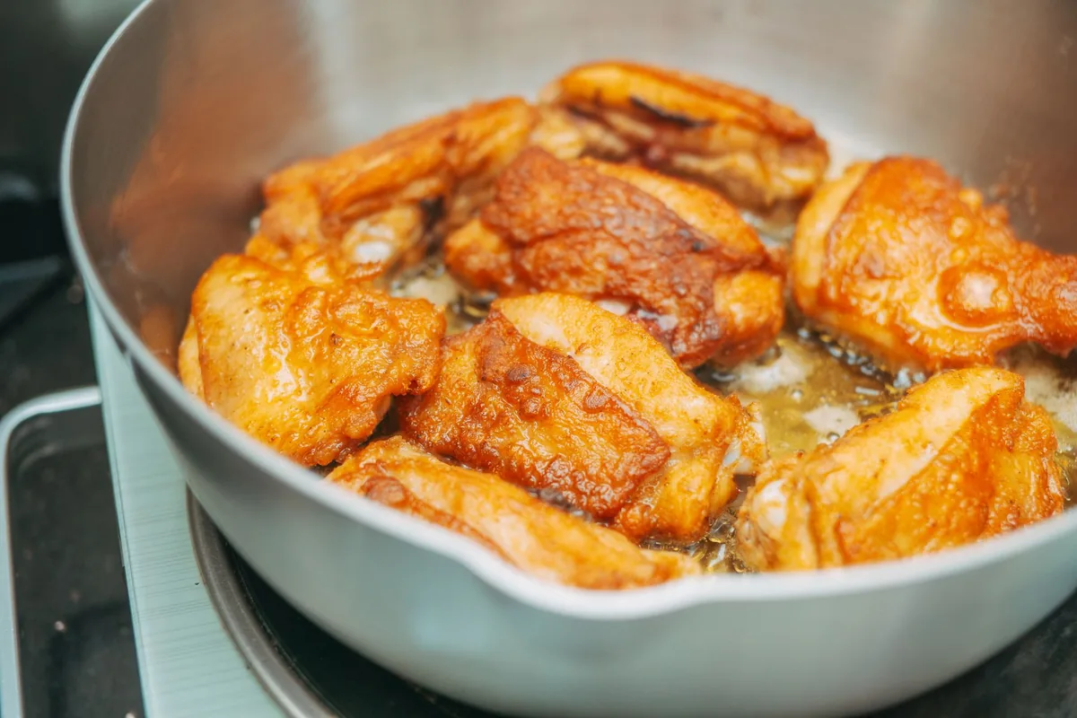 Chicken thighs browning skin side down in a wide stainless steel skillet