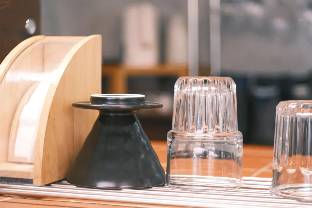 Upturned drinking glasses beside a dripper on a drying rack