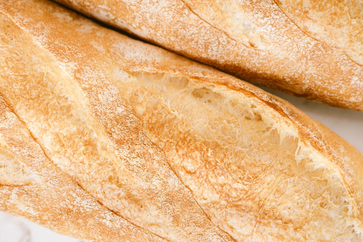 Close view of a golden, crackled sourdough crust with a dusting of flour