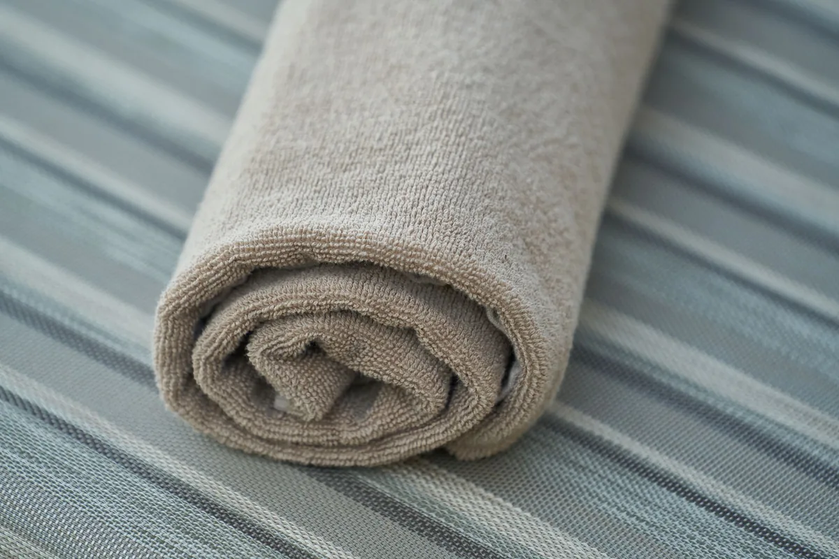 A rolled cloth towel on a striped surface