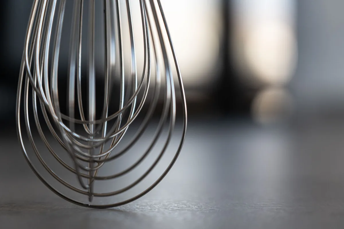 A balloon whisk standing on a dark counter