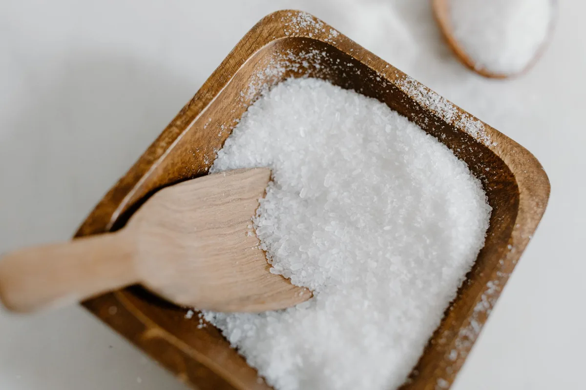 Coarse white salt in a wooden bowl with a small scoop