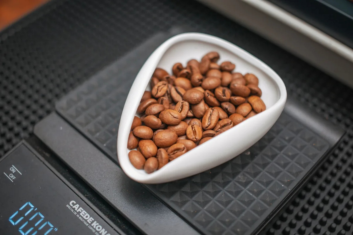 Coffee beans being weighed on a small digital scale