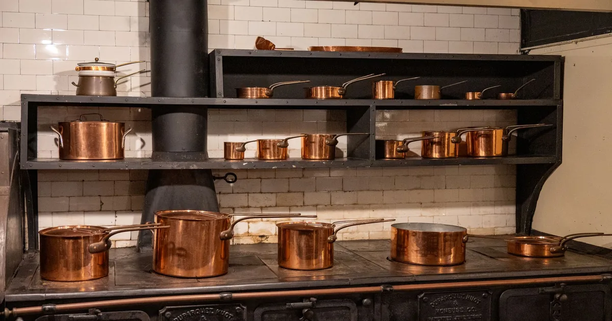 Copper pots and saucepans on a stove and shelf