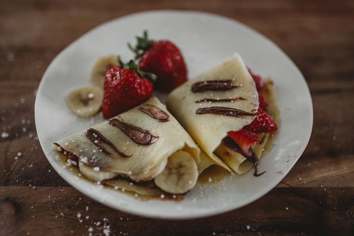 Crepes folded with strawberries and banana on a plate