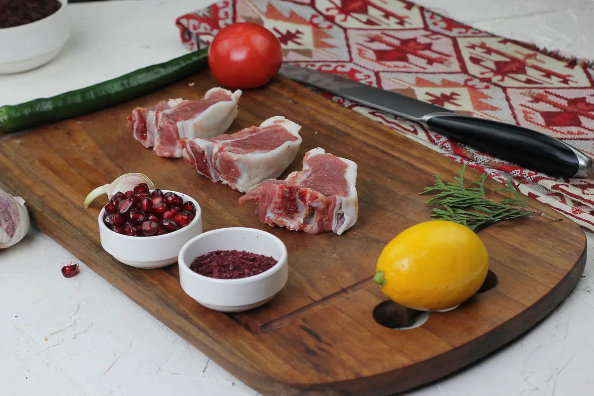 Cubed raw meat and a knife on a wooden board