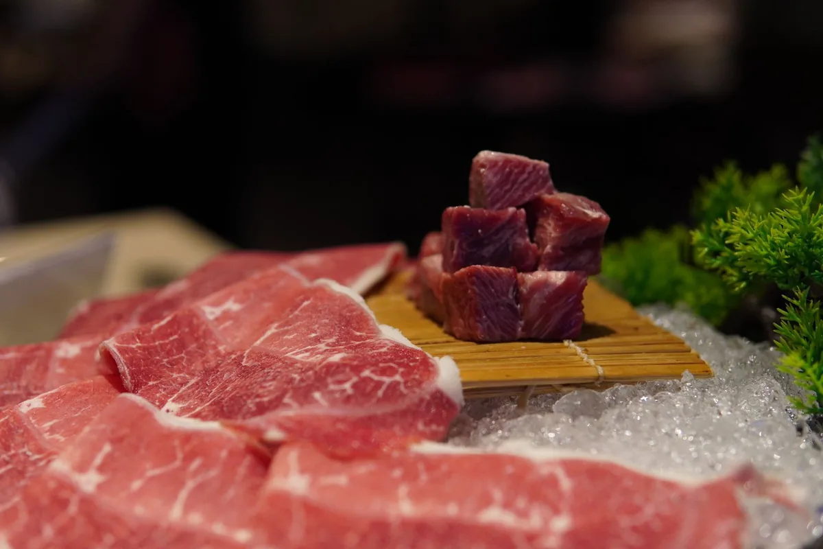 Cubes of raw red beef with white fat on a wooden cutting board