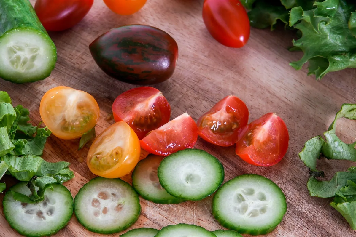 Cucumber slices, tomatoes and lettuce on a wooden board