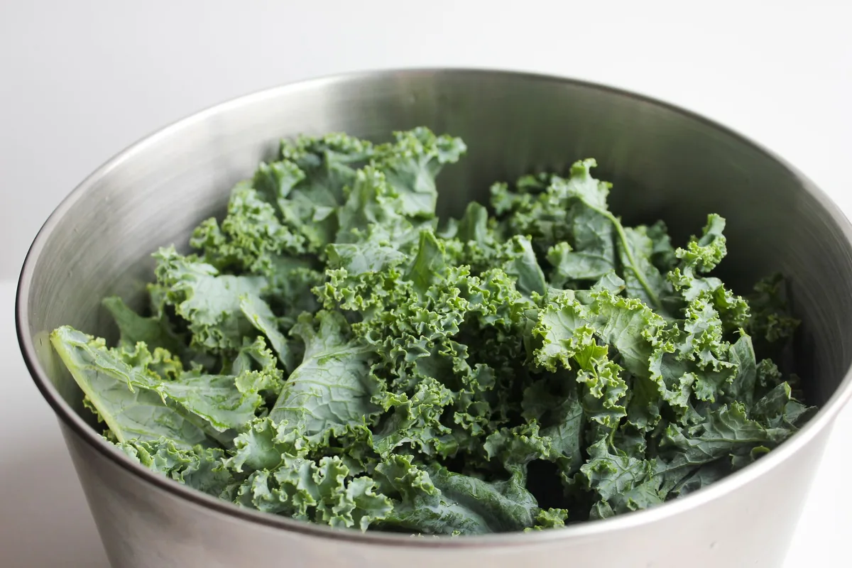 Curly green kale leaves in a stainless steel bowl