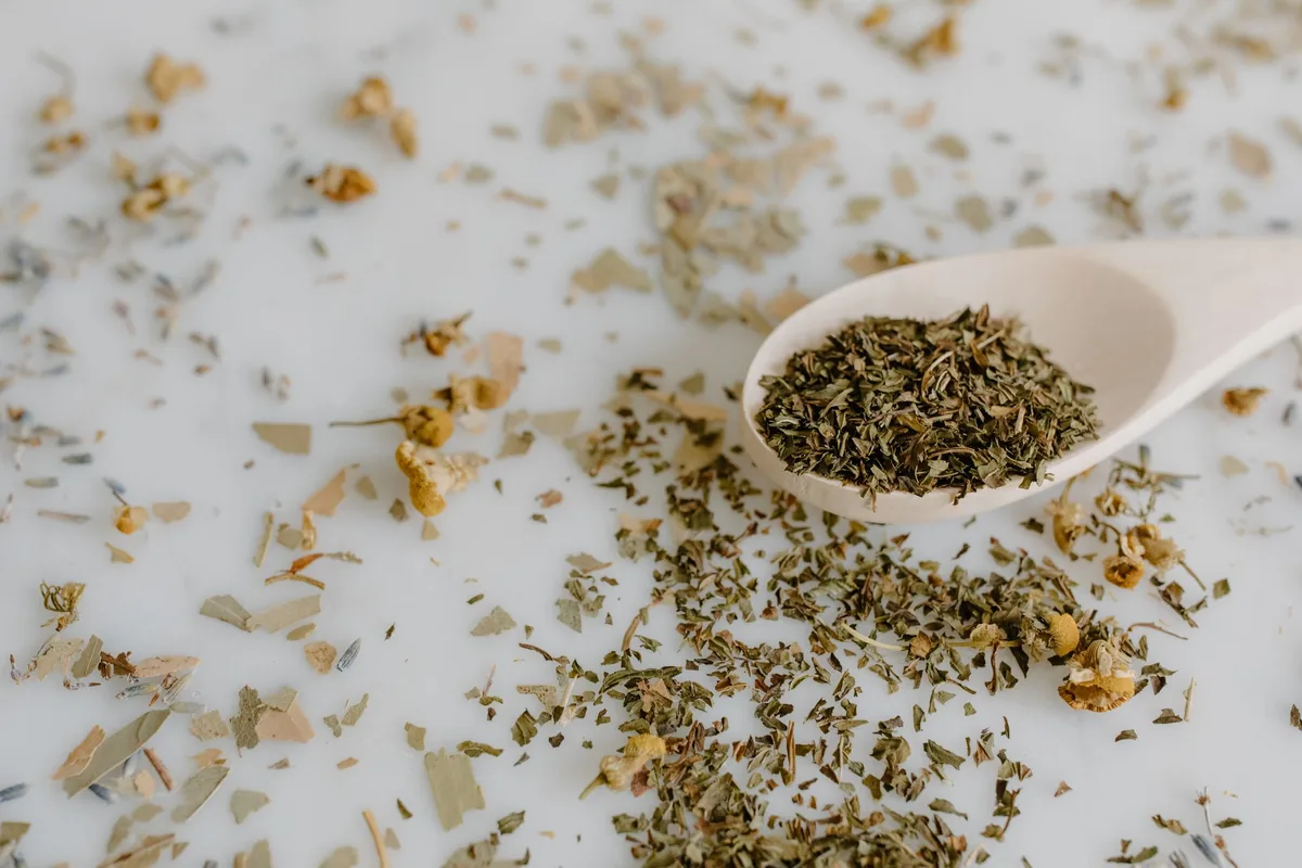 Dry loose leaf tea heaped on a wooden spoon