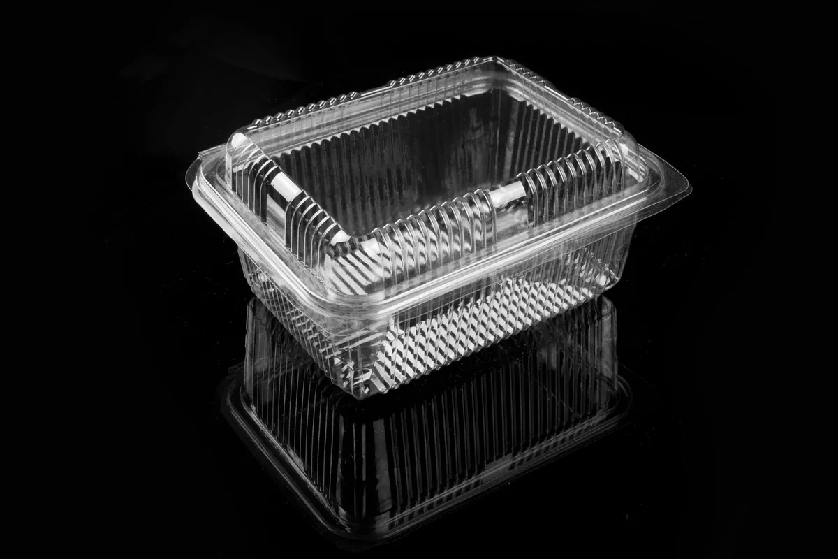 Empty clear plastic food containers with their lids laid out separately on a white counter