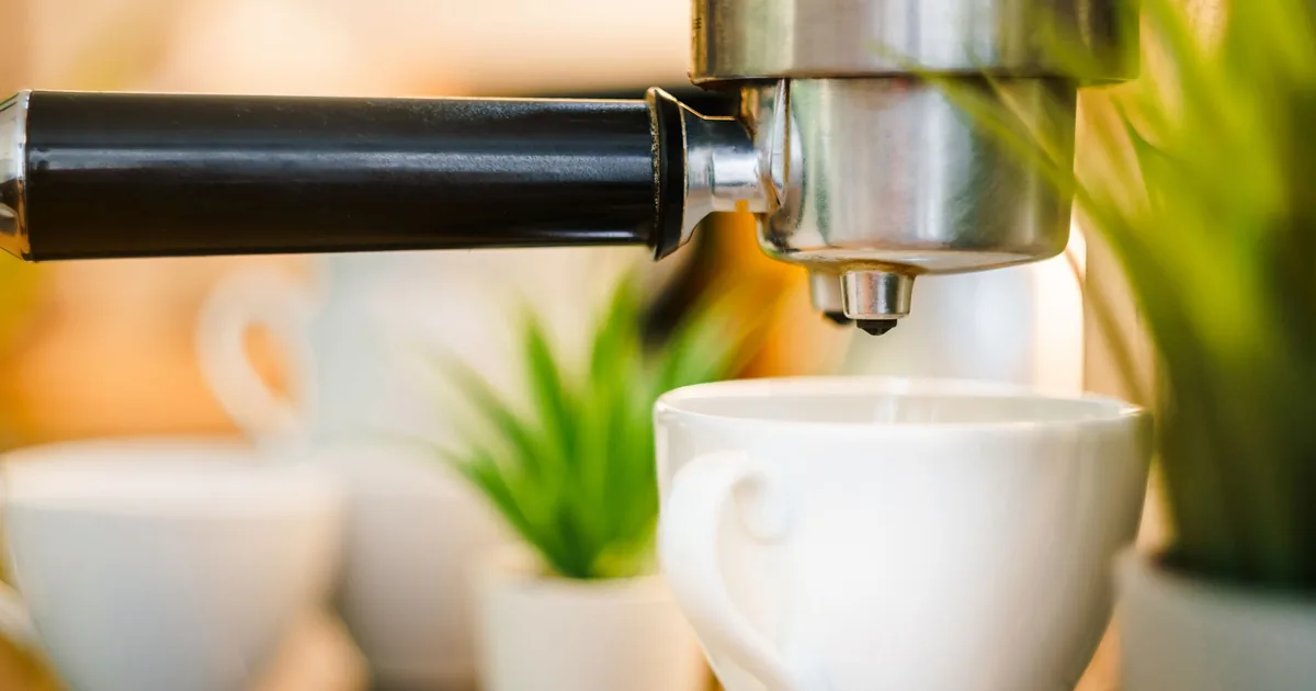 Espresso pouring from a portafilter into a white cup