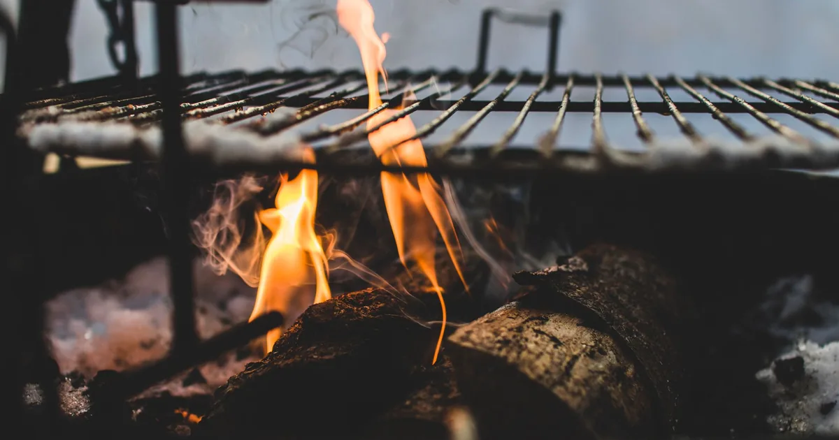 Flames rising beneath a metal grill grate
