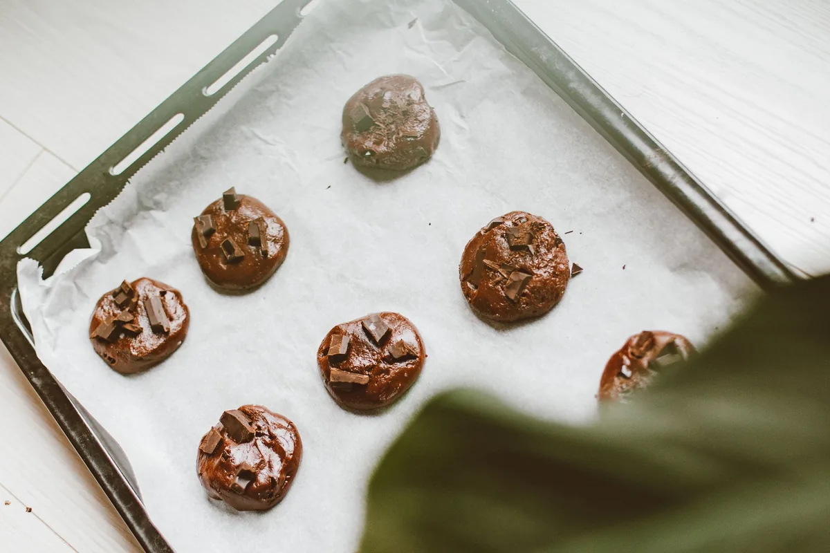 Freshly baked round chocolate chip cookies of matching size on a baking tray