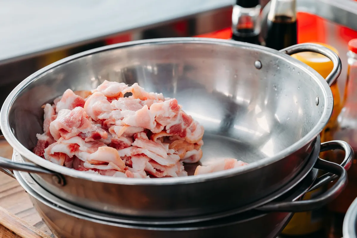 Freshly ground raw meat in a stainless steel mixing bowl on a light worktop