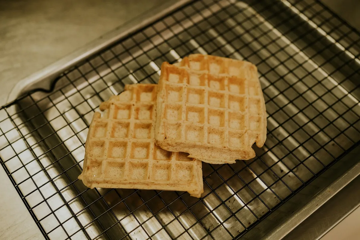 Freshly made waffles cooling on a metal wire rack on a light surface