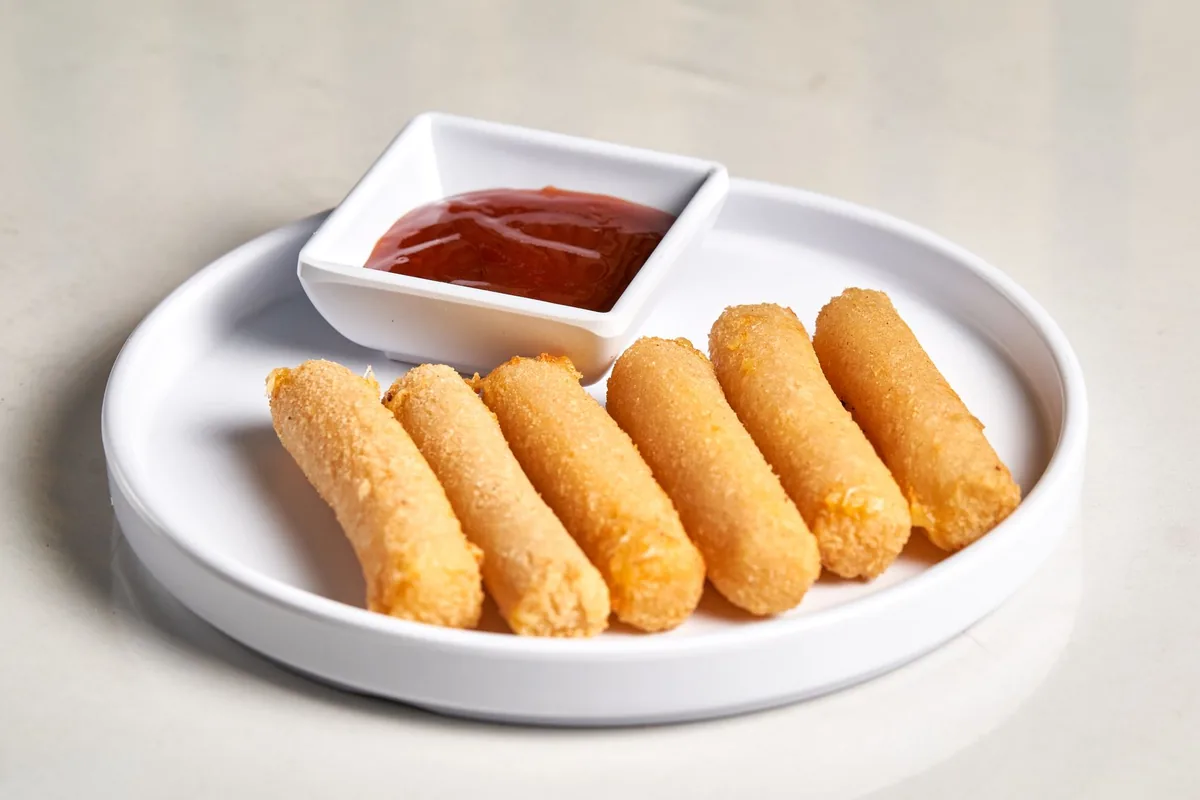 Fried mozzarella sticks with a cup of marinara sauce