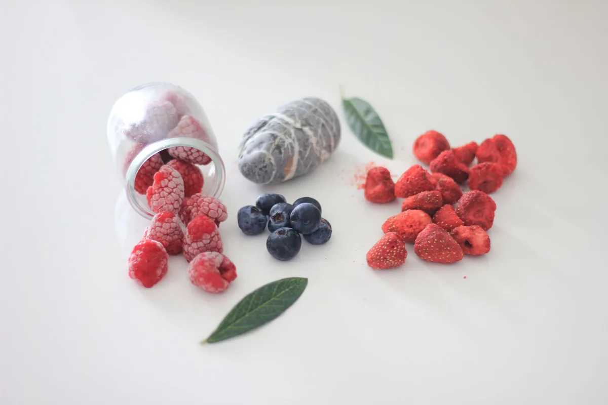 Frozen raspberries and blueberries on a white surface
